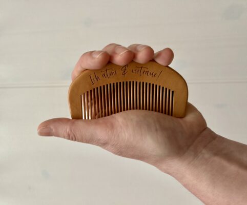 Geburts Kamm aus Holz wird in der Hand gehalten